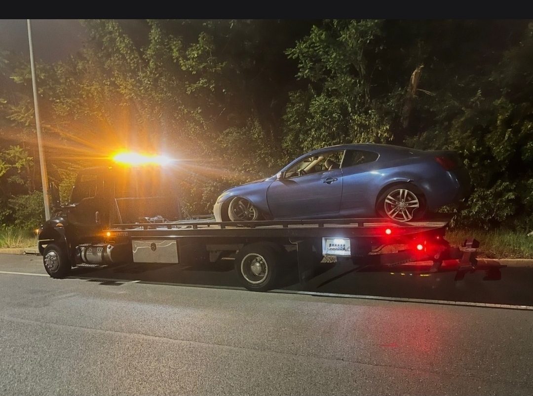 BML Towing flatbed loading an Infiniti coupe at night in Baltimore